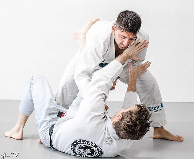 Two Jiu Jitsu practioners in white gis grappling