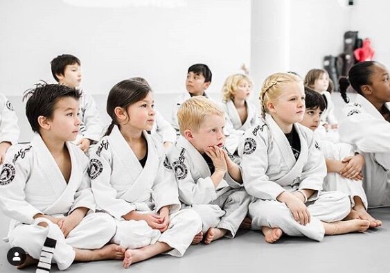 Children jiu-jitsu practitioners listening to instructor